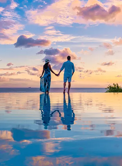Romantic silhouette of a couple at the edge of the infinity pool facing the sunset at the 4-star La Créole Beach Hotel & Spa in Le Gosier.
