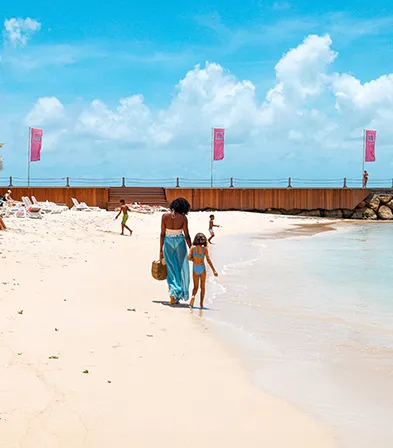 A complicit moment between a mother and her daughter walking on a tropical beach in Guadeloupe.