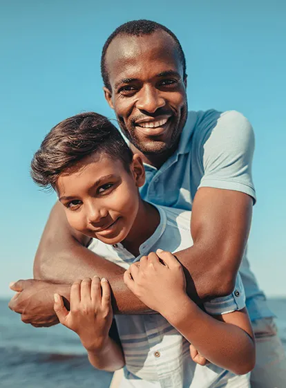 Father and son smiling facing the ocean in a moment of complicity in Guadeloupe near La Créole Beach Hotel & Spa.