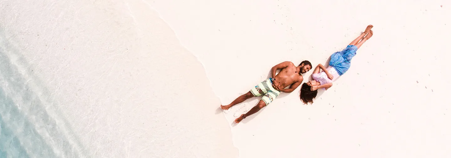 Pareja disfrutando de un momento de relax en una playa tropical de arena blanca.