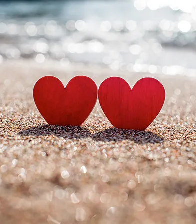 Symbols of love placed on the sand of a tropical beach by the sea.