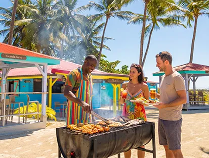 Sur une plage de Guadeloupe, un couple se rassemble autour d'un barbecue, partageant un moment chaleureux.