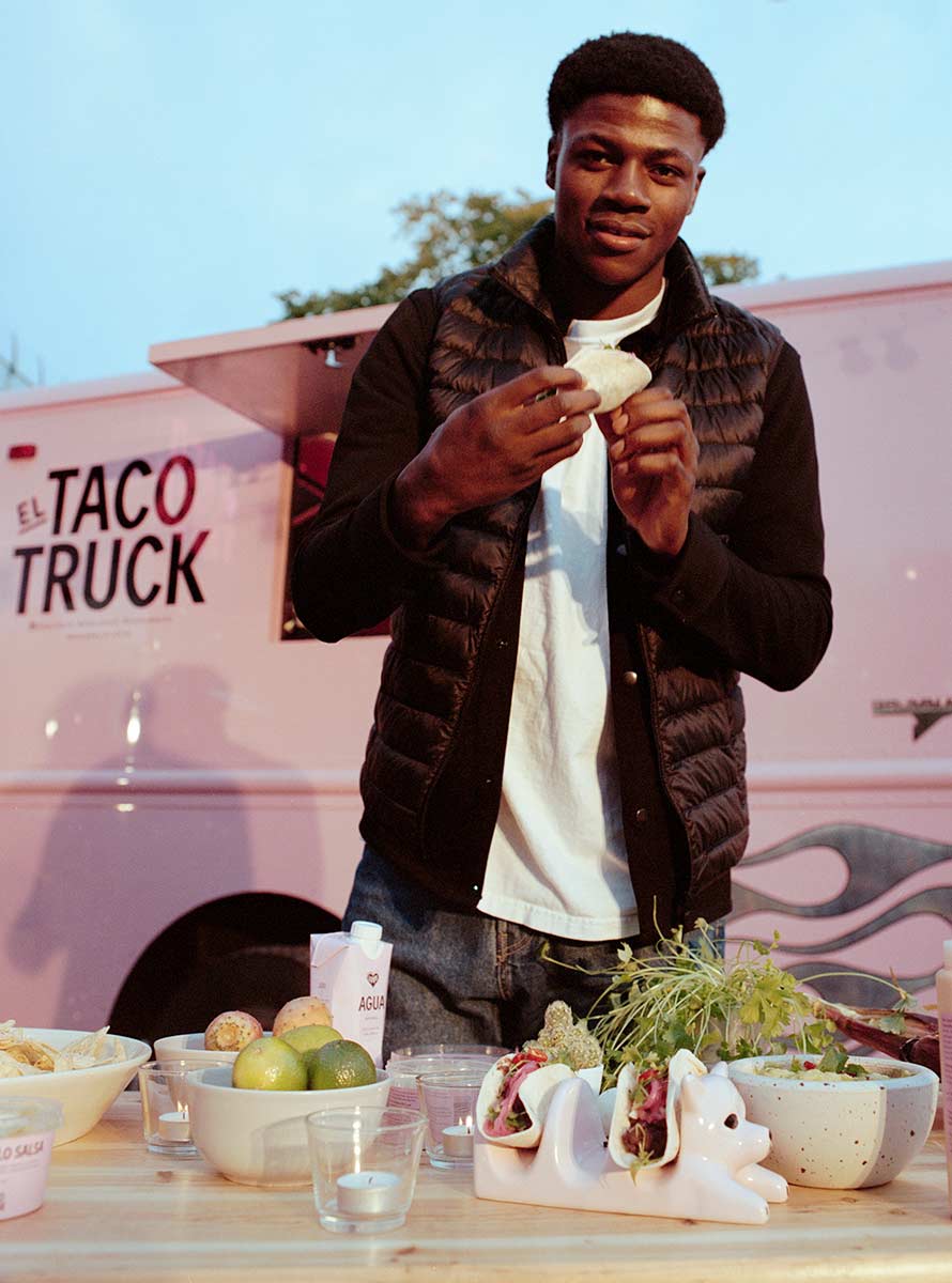 Person som står vid ett bord med tacos framför El Taco Trucks foodtruck