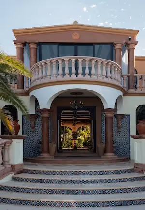 Main entrance of a prestigious residence with neoclassical architecture, stone balustrades, and a view leading through to an interior patio.