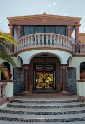 Main entrance of a prestigious residence with neoclassical architecture, stone balustrades, and a view leading through to an interior patio.