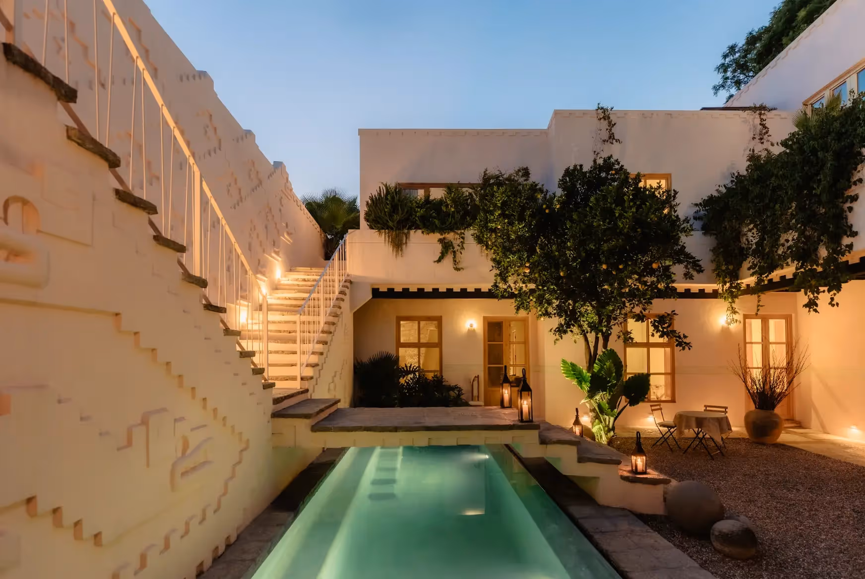 Luxurious inner courtyard at La Valise hotel featuring a narrow pool, tree, cafe tables, and pink colonial-style architecture.