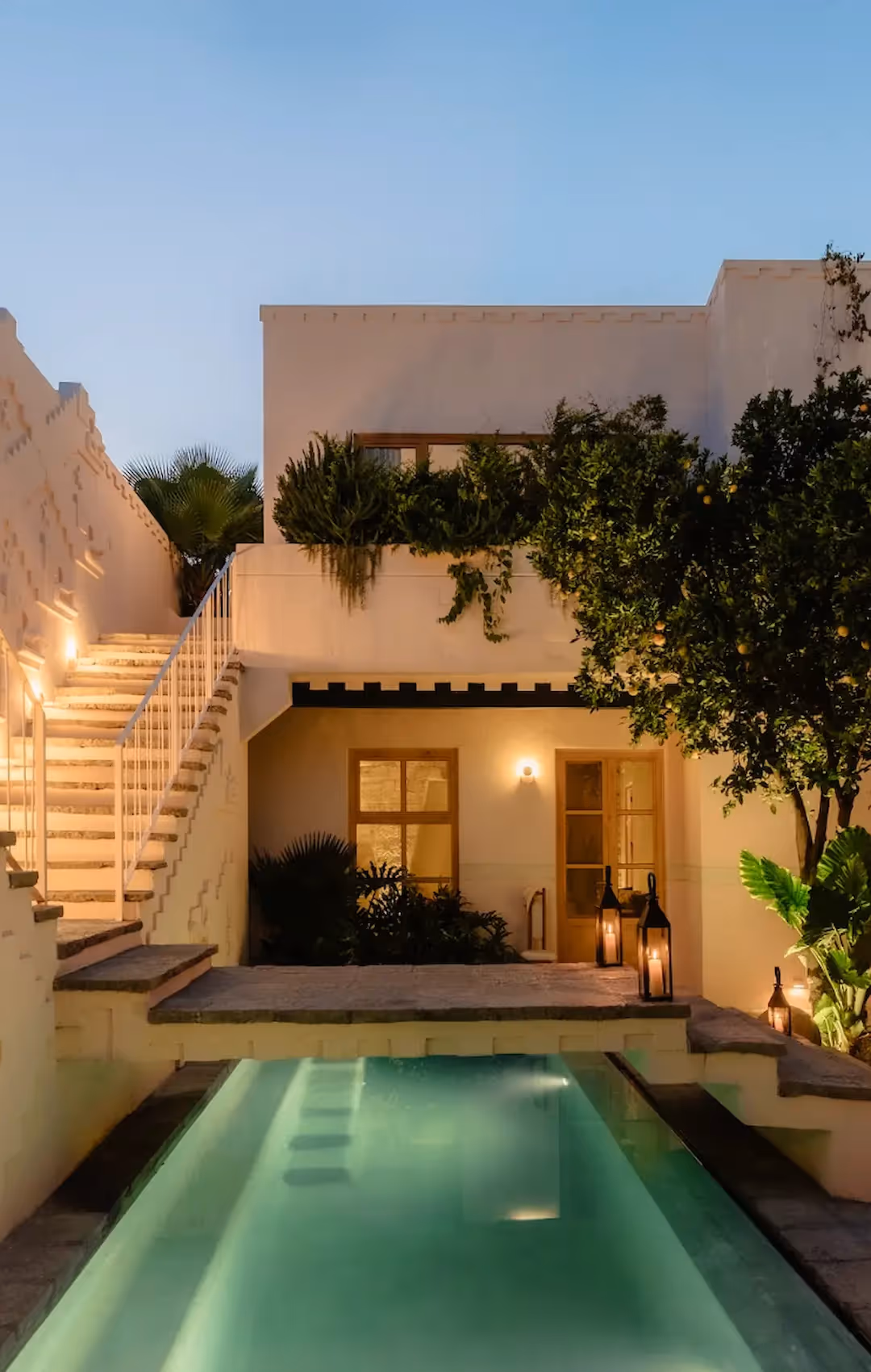 Luxurious inner courtyard at La Valise hotel featuring a narrow pool, tree, cafe tables, and pink colonial-style architecture.