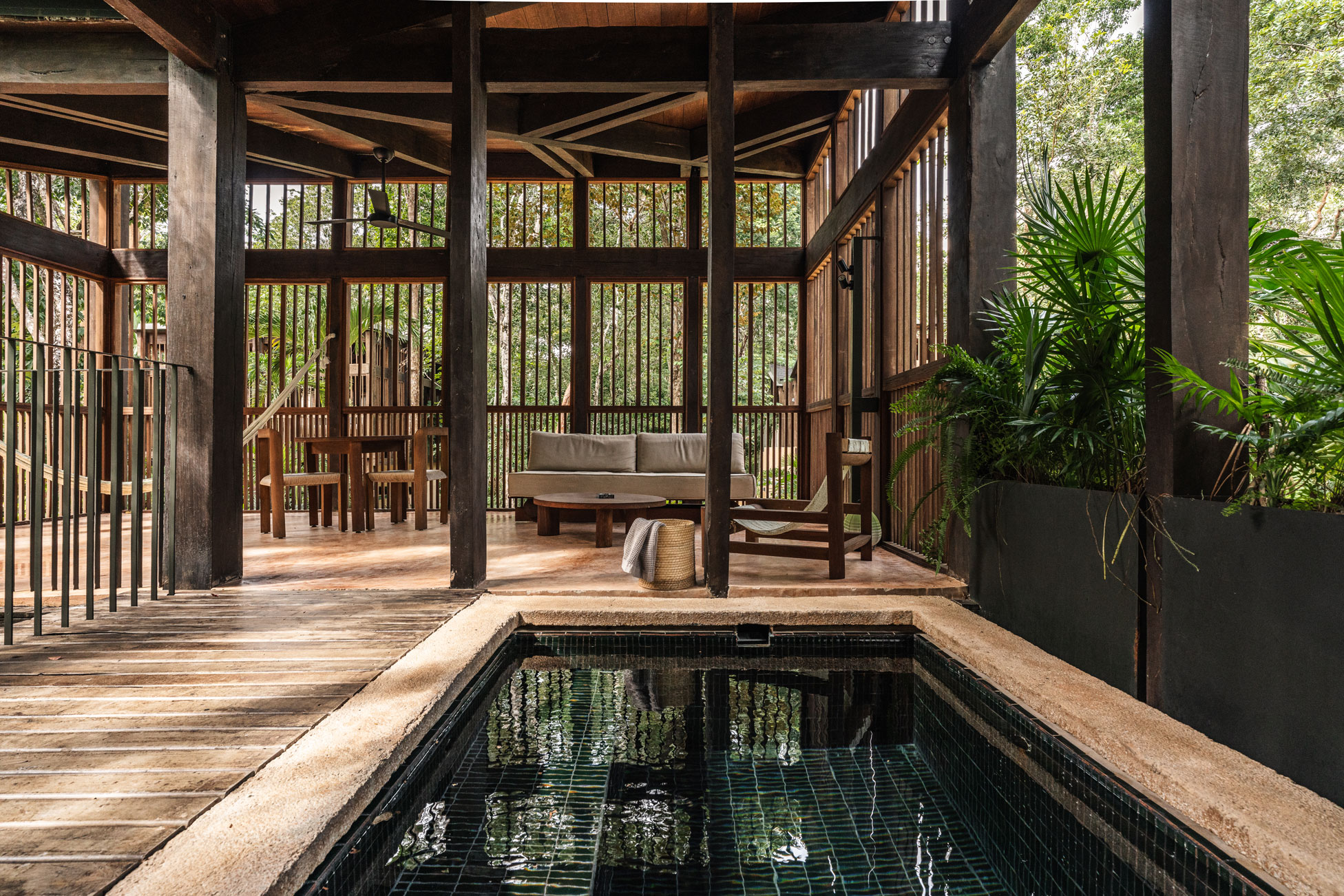 Elevated modern architectural cabin in the jungle featuring wooden slatted windows and terracotta details.