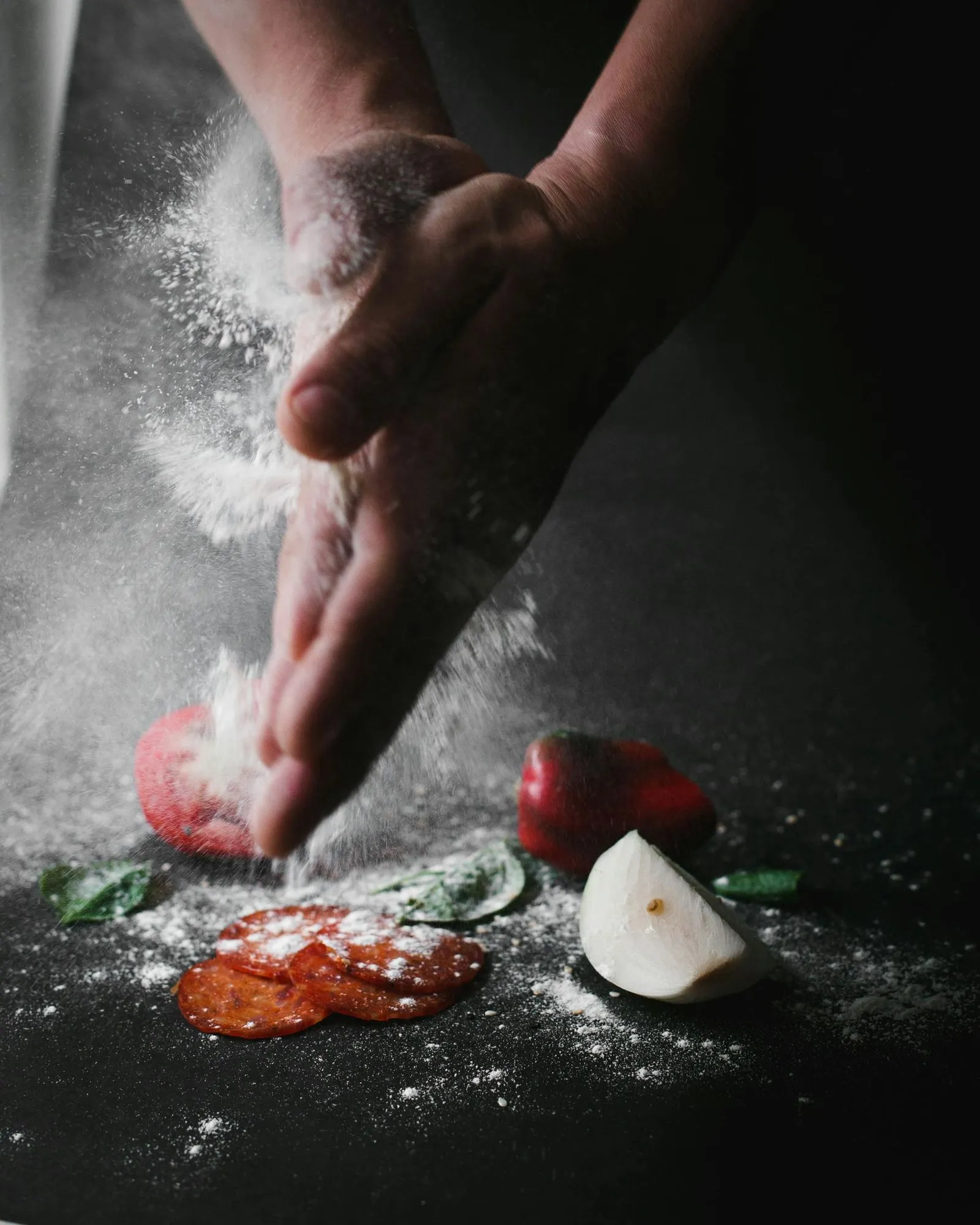 A person is sprinkling flour on some food.