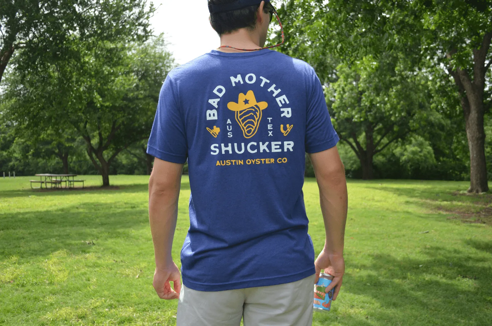 A man wearing an Austin Oyster Co. shirt at a park.