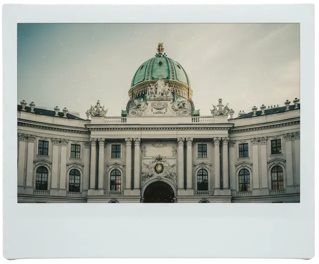 Historisches Gebäude mit grünem Kuppeldach und klassizistischer Fassade bei bewölktem Himmel.