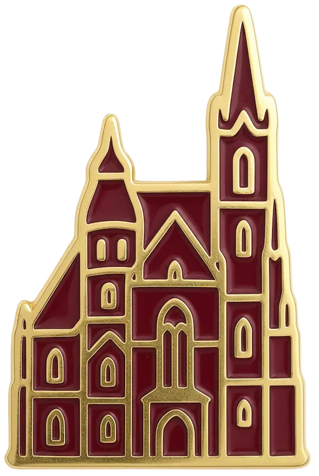 Goldener Anstecker in Form einer Kathedrale mit roten Flächen und spitzen Türmen.