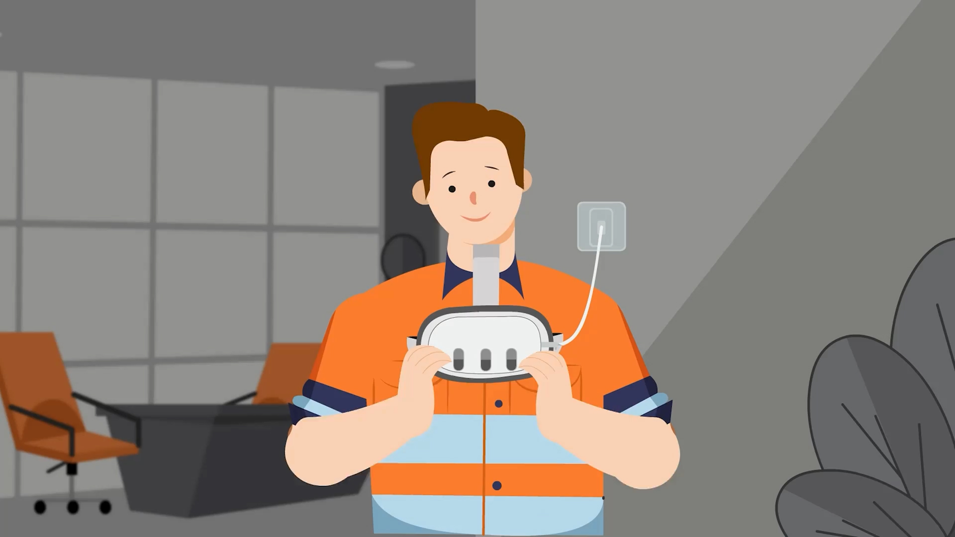 Person in an orange safety vest holding and charging a VR headset connected to a wall outlet in an office room.