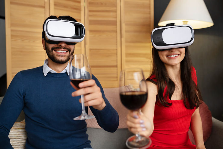 A man and woman enjoy a virtual reality experience while holding glasses of wine, immersed in a digital world together.