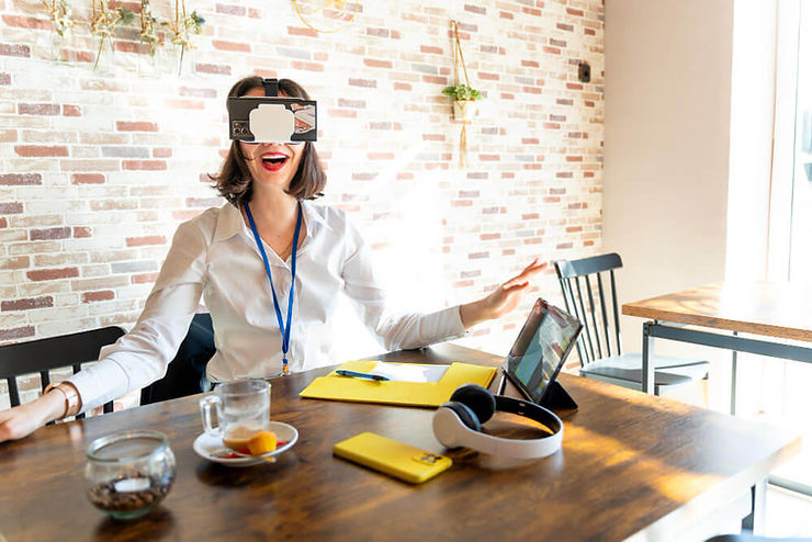 A woman seated at a table, immersed in a virtual reality experience while wearing VR glasses.