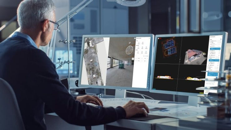 A man focused on two computer screens, utilizing NavVis IVION for his work tasks.