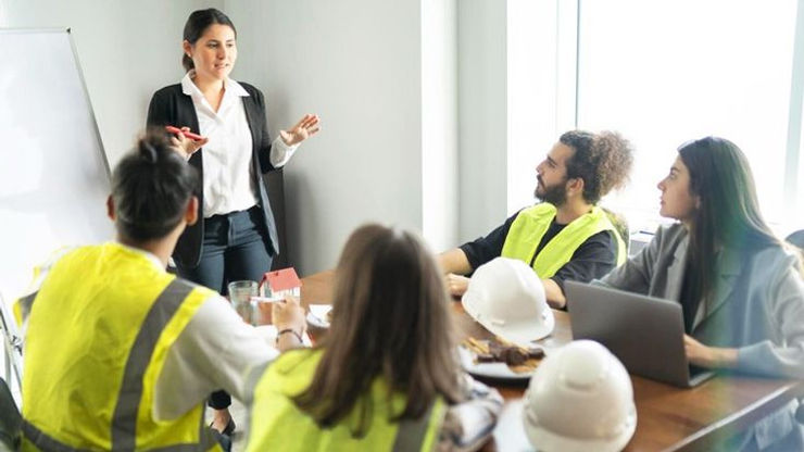 A woman in a safety vest addresses a group, sharing insights and knowledge on safety practices during her presentation.