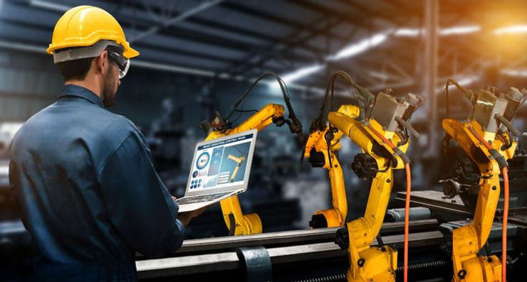 A construction worker in a hard hat and helmet is engaged in using a laptop for work-related tasks.