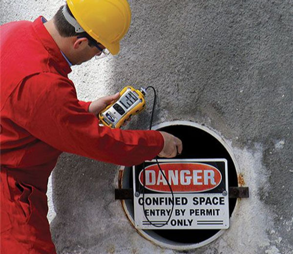 A man dressed in red examines a manhole with a meter, assessing its safety and functionality for public use.