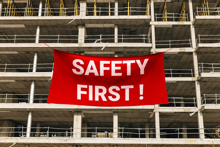 A red safety first sign is suspended from a building, highlighting the importance of safety in the surrounding area.