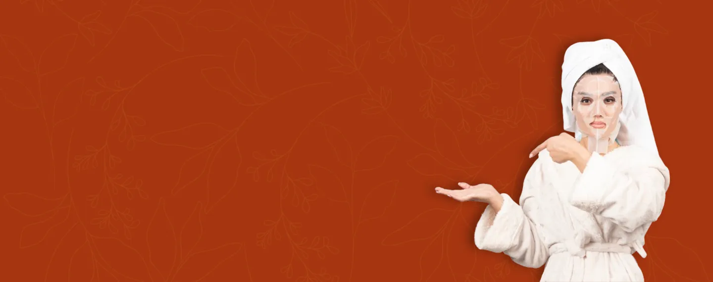 Woman in a white bathrobe and towel with a transparent face mask pointing to the left on an orange background with subtle leaf patterns.