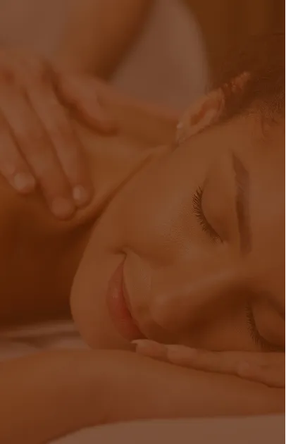 Woman with eyes closed smiling while receiving a shoulder massage.