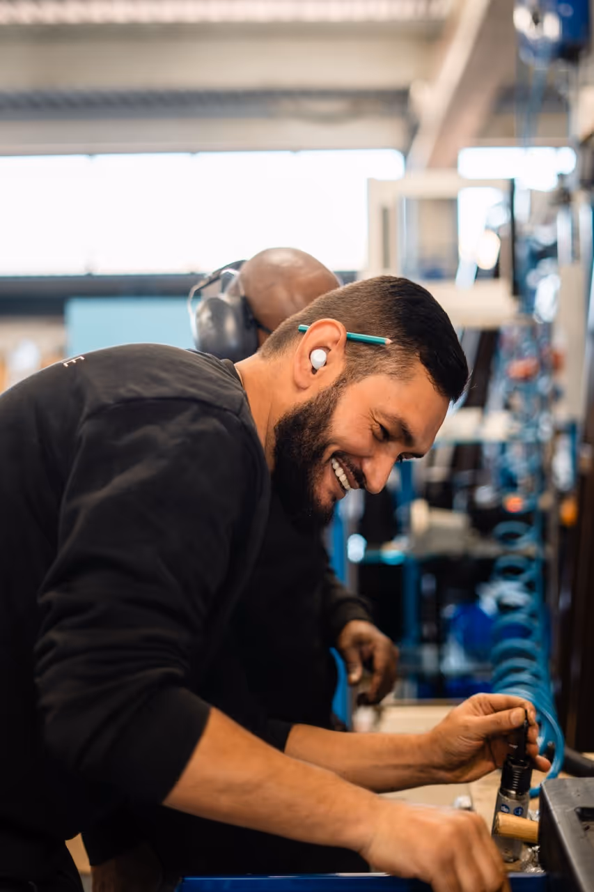 Un homme vue de prêt souriant faisant le montage d'un chassis de fenêtre