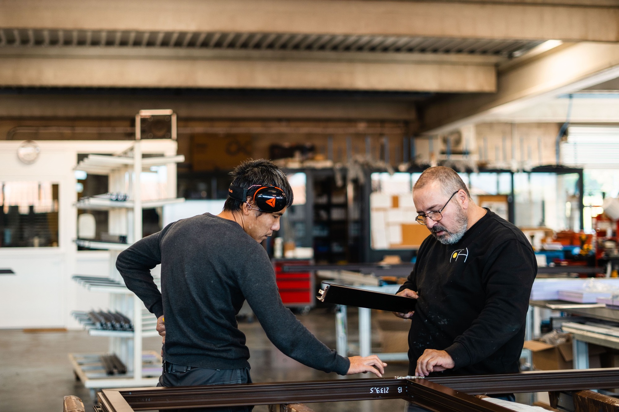 deux hommes dans un atelier de cintrage de menuiserie devant un établis d'assemblage