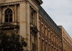 Historic stone building with arched windows under a cloudy sky.