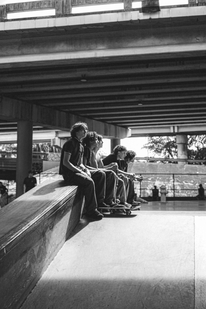 kids sitting together on a rail in a skate park