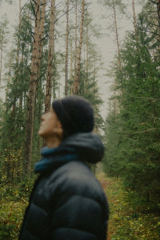 man standing in the woods looking upward and to the left off frame
