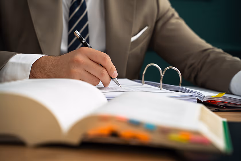 Adwokat Kancelarii Czarnota w Gdańsku przygotowuje opinię prawną, notując w dokumentach i analizując przepisy