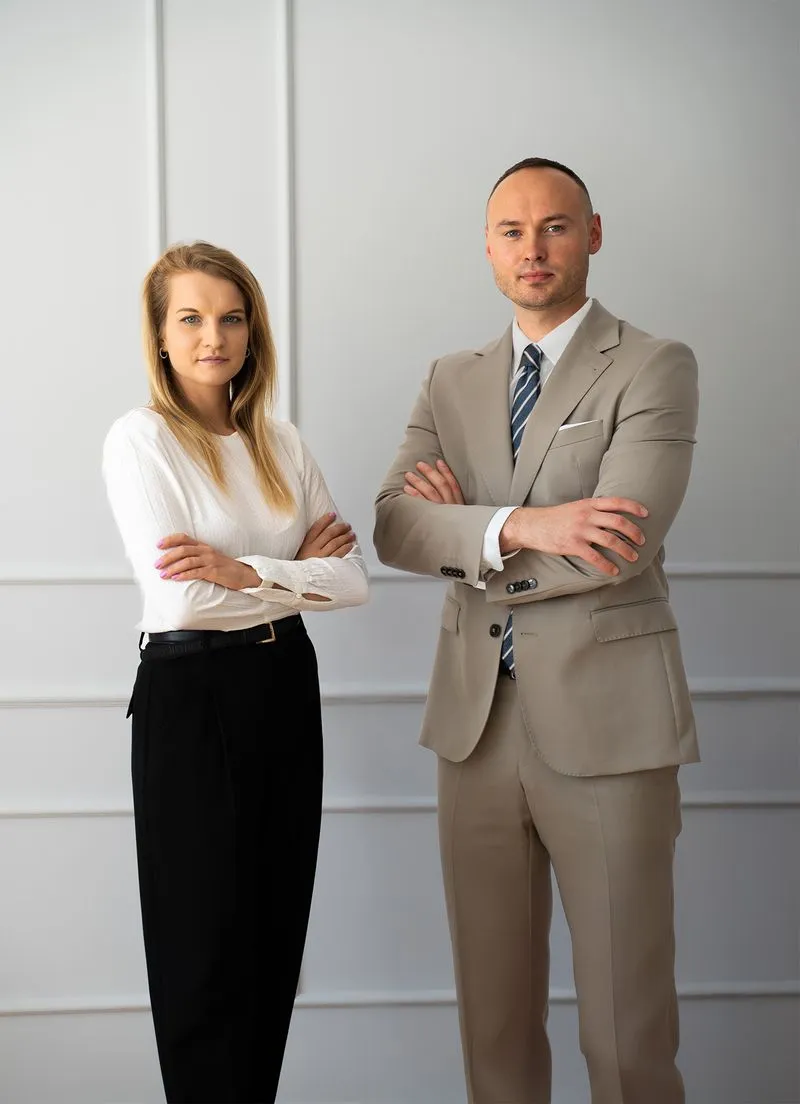 Profesjonalny mężczyzna w beżowym garniturze i kobieta w białej bluzce pozująca w nowoczesnym biurze
