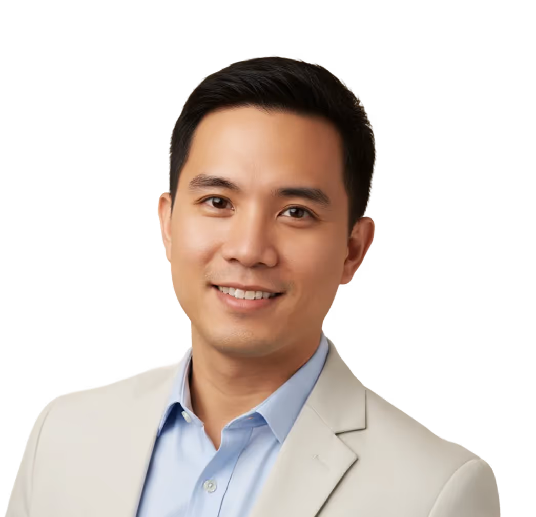 Smiling man with short black hair wearing a light blue shirt and beige blazer against a transparent background.