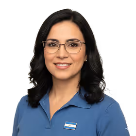 Smiling woman with shoulder-length dark hair wearing glasses and a blue collared shirt with a name badge.