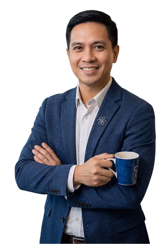 Smiling man in a blue blazer holding a blue coffee mug with crossed arms.