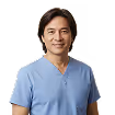 Smiling man with medium-length dark hair wearing light blue medical scrubs.