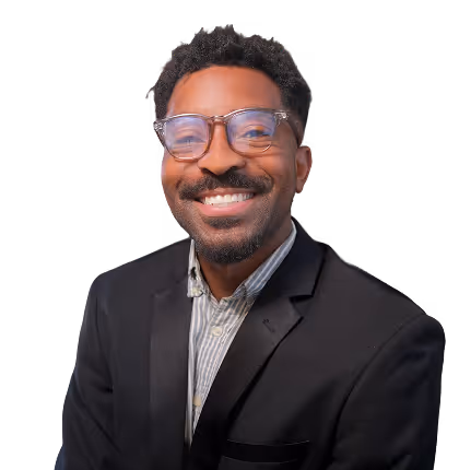 Smiling man with glasses wearing a black suit jacket and striped shirt against a transparent background.