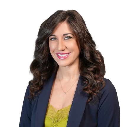 Woman with long curly brown hair wearing a navy blazer and green lace top smiling at the camera.