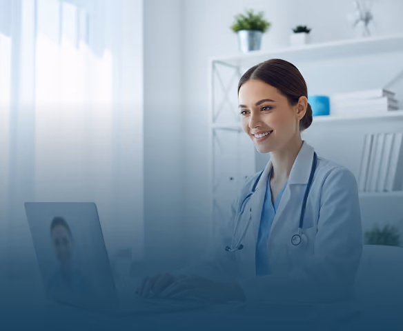 Smiling female doctor using laptop for telemedicine in a bright office with shelves and plants.