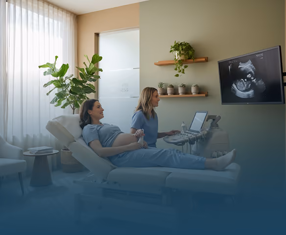 Pregnant woman having an ultrasound exam by a healthcare professional in a modern clinic room.