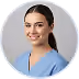 Smiling woman with dark hair wearing blue medical scrubs against gray background.