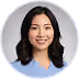 Smiling young woman with black hair wearing a light blue top on a white background.