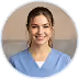 Smiling young woman with hair tied back wearing a blue scrub top in a professional setting.