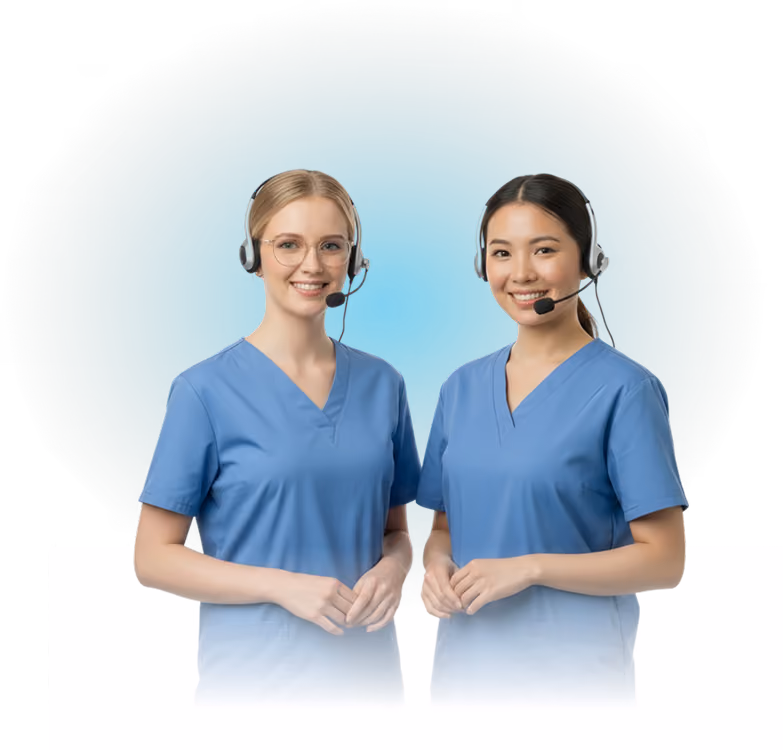 Two female healthcare workers in blue scrubs wearing headsets and smiling at the camera.