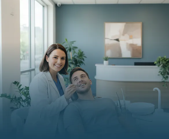 Smiling female dentist in white coat holding a dental mirror near a male patient seated in a dental chair, inside a modern dental office with plants and artwork on the wall.