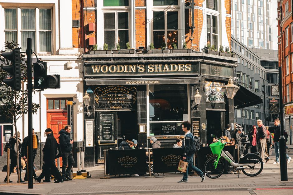 Lively urban street scene outside Woodin's Shades pub in London, showcasing city life and architecture.