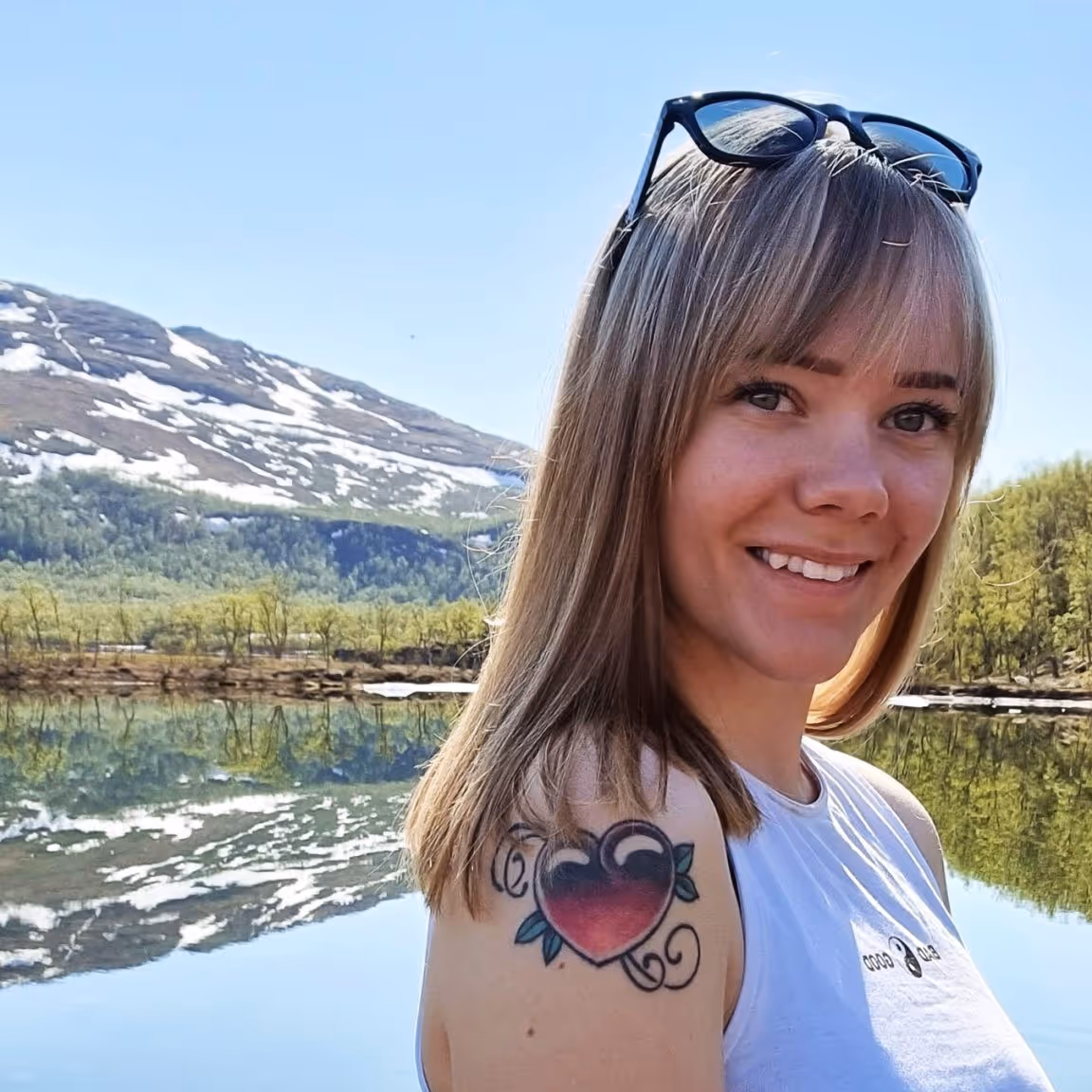 Sandra Elise, en renholder hos Vaskehjelp, smiler til kameraet med fjell og vann i bakgrunnen