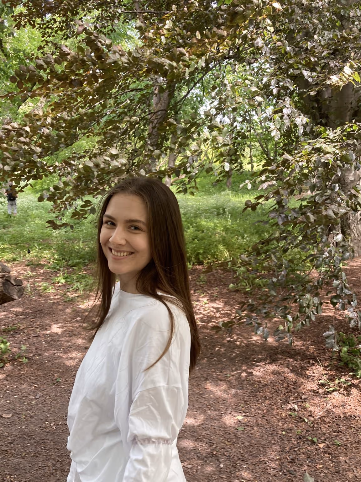 Daria, a cleaner at Vaskehjelp, smiles at the camera outdoors in nature.