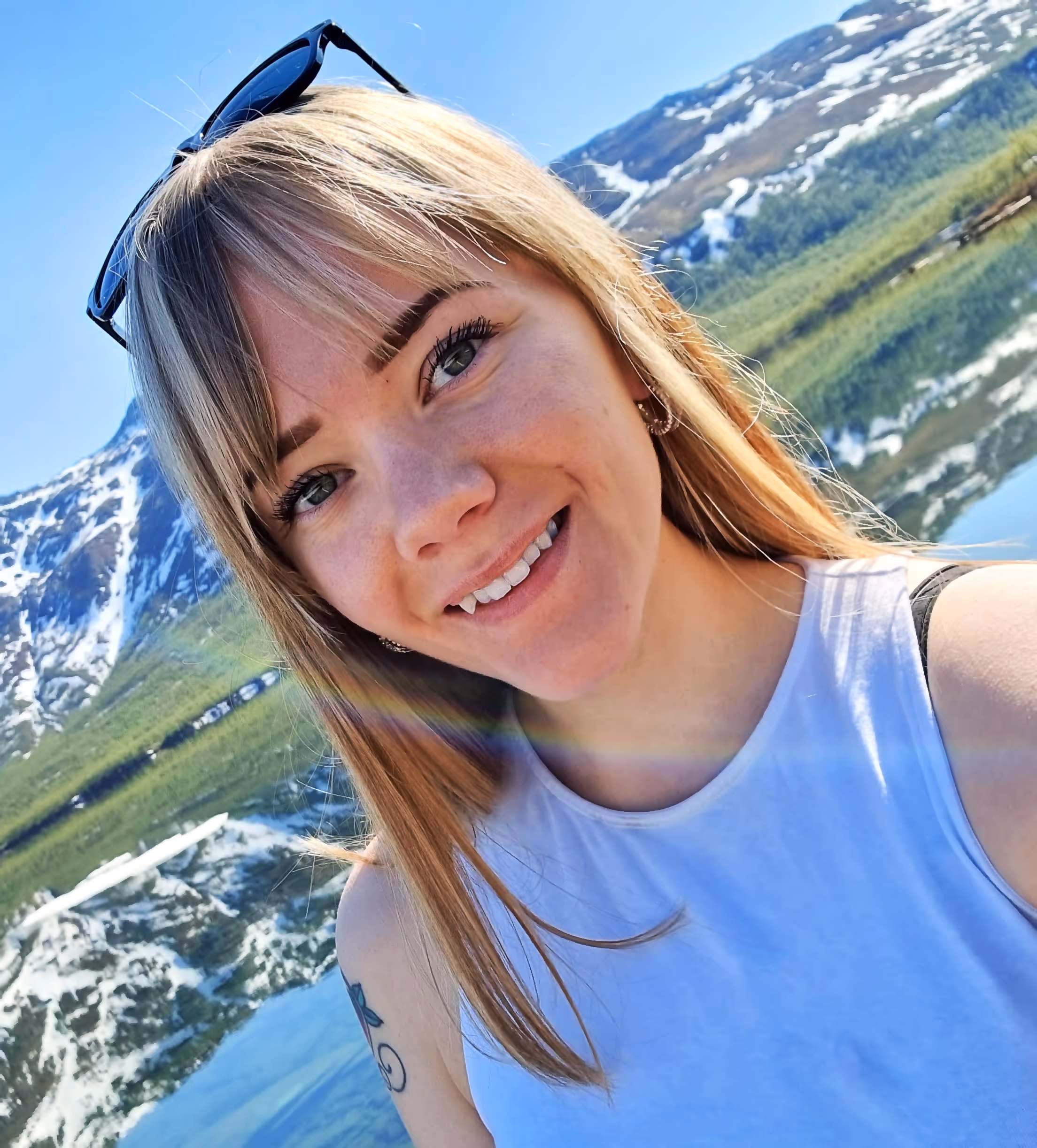 Sandra Elise, a cleaner at Vaskehjelp, smiles at the camera with mountains and water in the background.